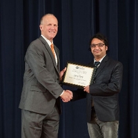 Doctor Potteiger posing for a photo with an award recipient in a black jacket